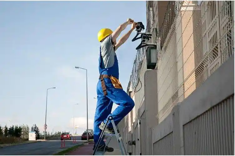 Security technician on a ladder installing a CCTV camera