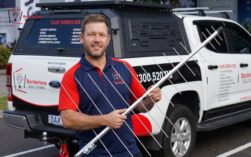 Borderless Solutions technician holding TV antenna with masthead amplifier - signal boosting for long cable runs