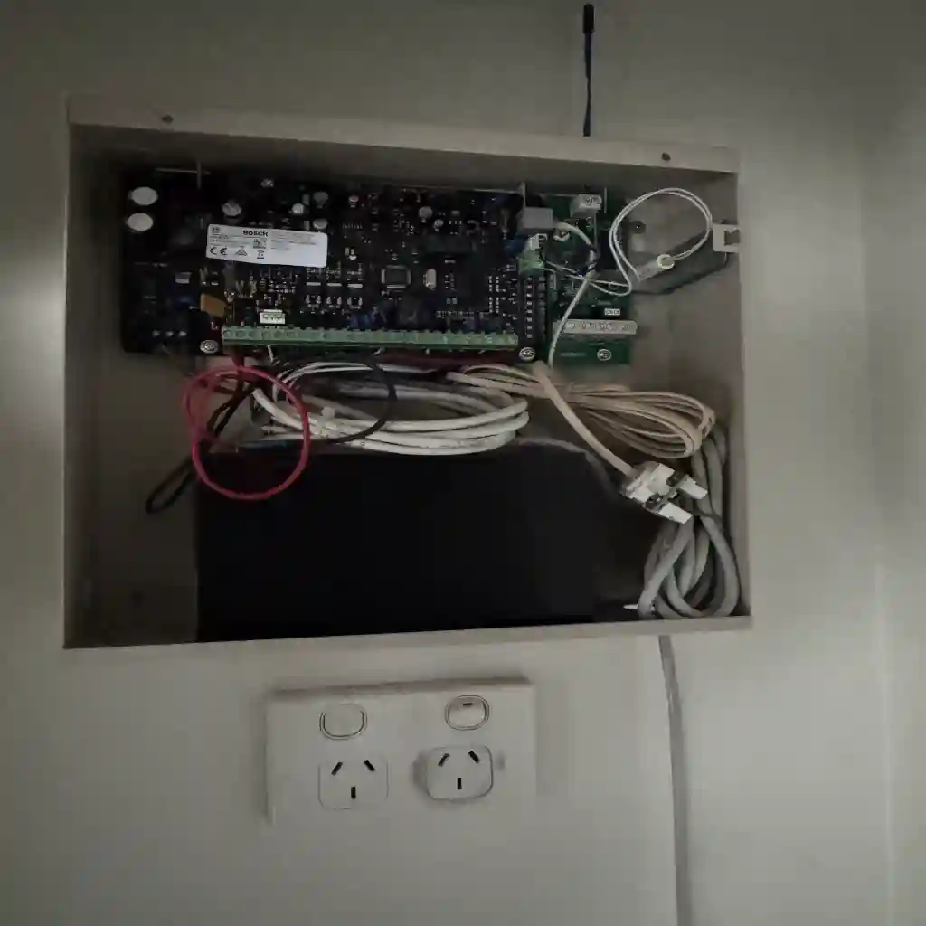 Alarm cabinet mounted above a power outlet in a Mitcham service cupboard