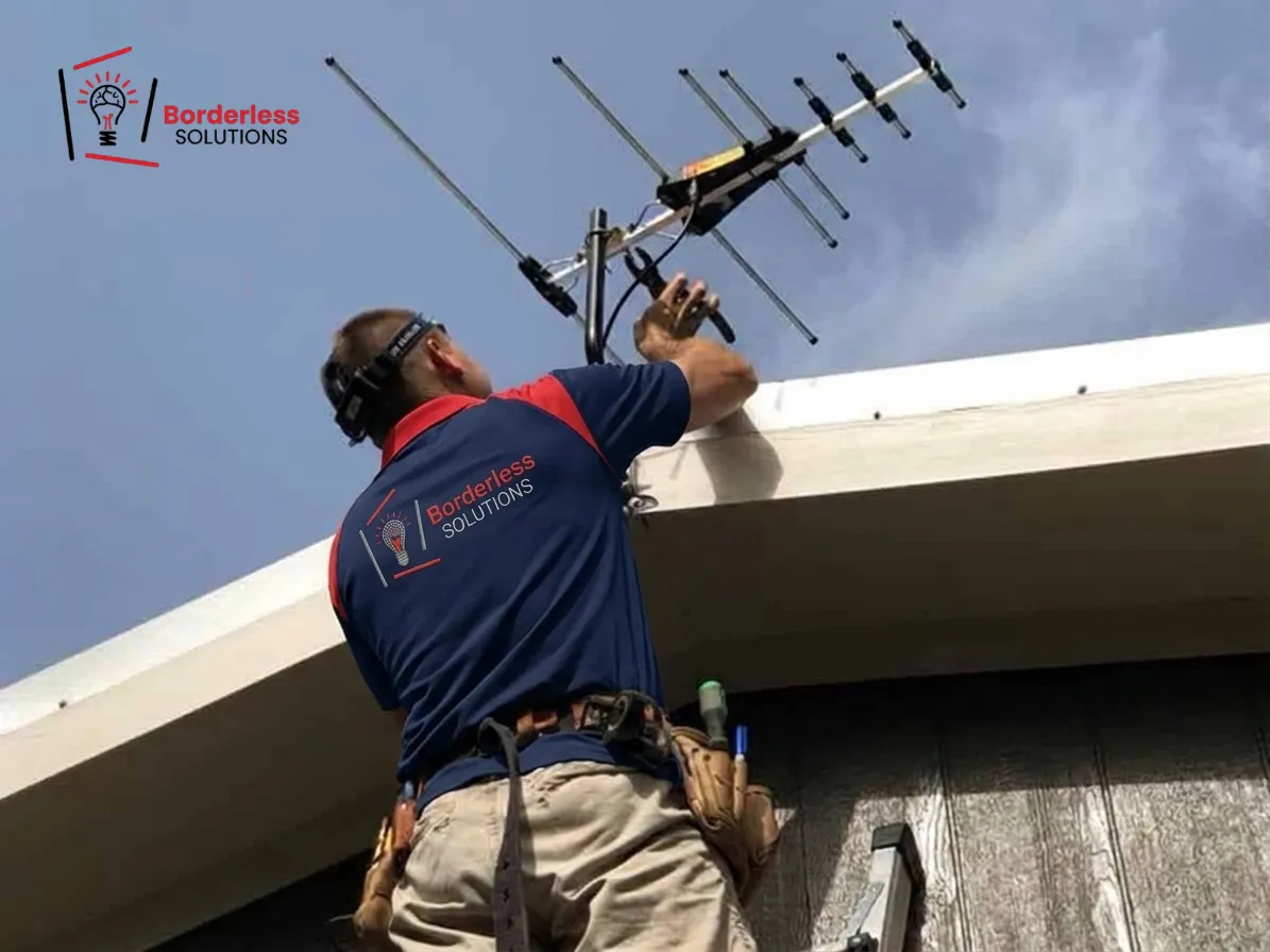 Borderless Solutions technician installing Yagi TV antenna on rooftop edge - commercial and rental property antenna installation Melbourne