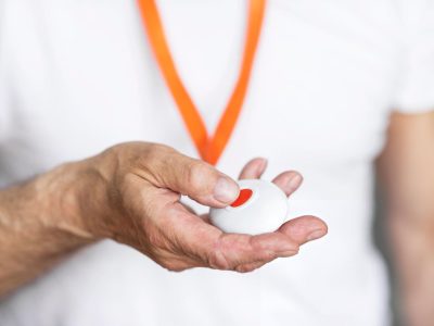 personal-alarm-melton Close-up of an elderly person holding a personal alarm pendant with emergency button. Borderless Solutions provides personal alarm installation, CCTV, intercoms, access control, and smart security solutions in Melton.